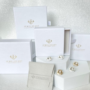 May include: Four white boxes with the logo 'Jewelheart - California 2013' and a small white pouch with the same logo. The boxes are arranged in a pyramid shape with the pouch in front.