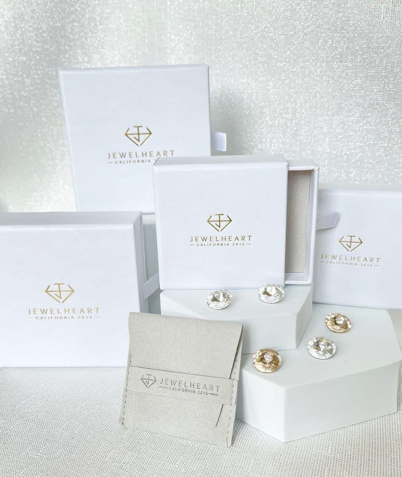 May include: Four white boxes with the logo 'Jewelheart - California 2013' and a small white pouch with the same logo. The boxes are arranged in a pyramid shape with the pouch in front.