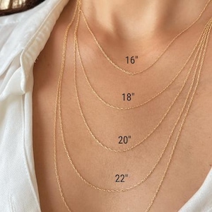 Five 14k solid yellow gold twisted rope chains of different lengths, 16 inches, 18 inches, 20 inches, 22 inches, and 24 inches, are layered on a model's neck. The chains are all the same width, 1mm.