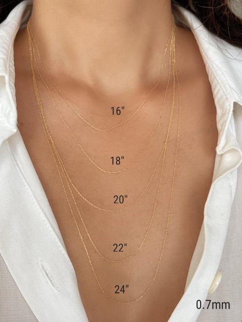 Five 14k solid gold twisted rope chains of different lengths, 16 inches, 18 inches, 20 inches, 22 inches, and 24 inches, are layered on a model's neck. The chains are all the same width, 0.7mm.