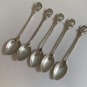 May include: Set of five silver teaspoons with ornate handles and a decorative design on the top of each handle.