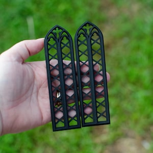 May include: Two black, decorative, gothic-style window panels with a diamond lattice design.