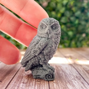 May include: A small gray owl figurine with detailed feathers and a perched position. The owl is sitting on a base with a circular design.
