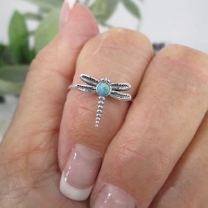 May include: A silver ring with a turquoise dragonfly design.