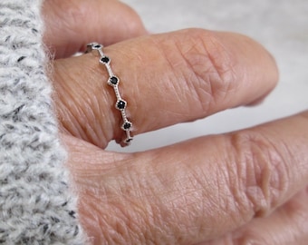 May include: A silver ring with a row of small black gemstones.