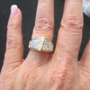 May include: A gold ring with a triangular shaped band set with small clear stones.