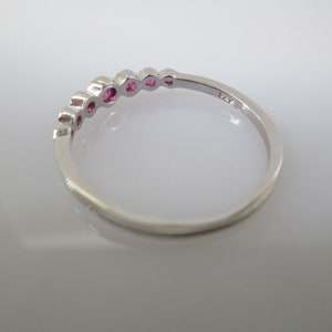 Pu&ograve; includere: Un anello a fascia d'argento con una fila di pietre preziose rosa incastonate nella fascia.