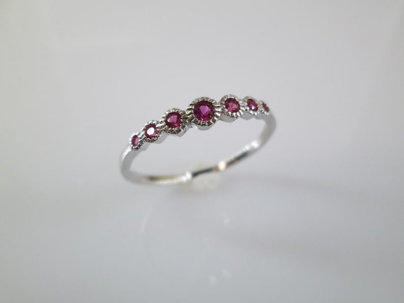 Pu&ograve; includere: Un anello d'argento con una fila di sei piccole pietre preziose rotonde rosa.
