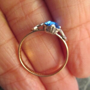 May include: A gold ring with a blue gemstone and silver accents.
