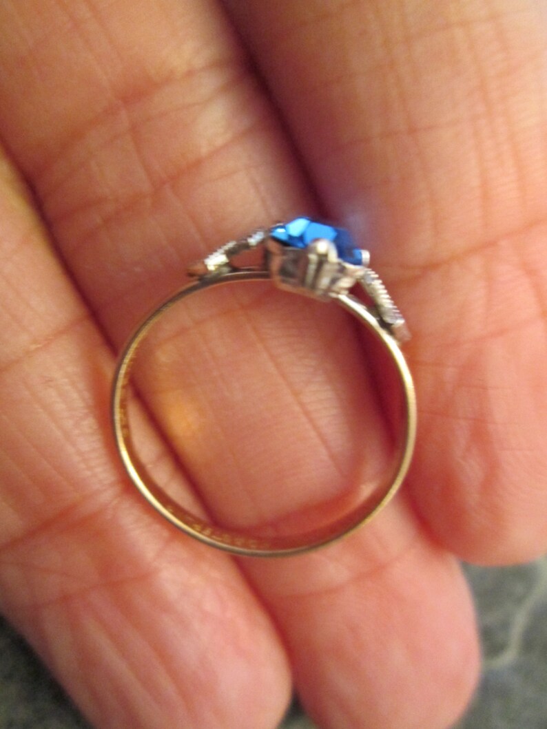 May include: A gold ring with a blue gemstone and silver accents.
