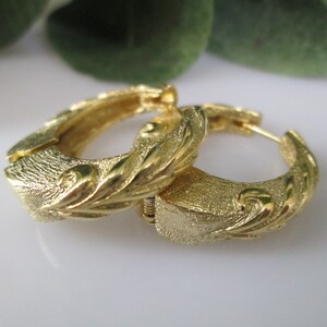 May include: Gold hoop earrings with a textured, leaf-like design.