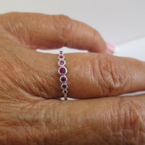 Pu&ograve; includere: Un anello a fascia d'argento con una fila di piccole pietre rotonde rosse.