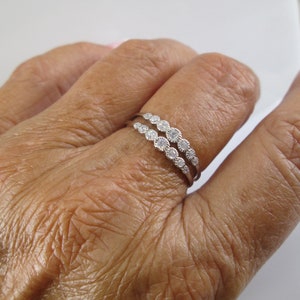 Pu&ograve; includere: Un anello d'argento con una doppia fila di piccole pietre trasparenti.