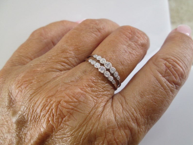 Pu&ograve; includere: Un anello d'argento con una doppia fila di piccole pietre trasparenti.