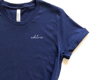 May include: A navy blue t-shirt with the word "editrix" embroidered on the front.