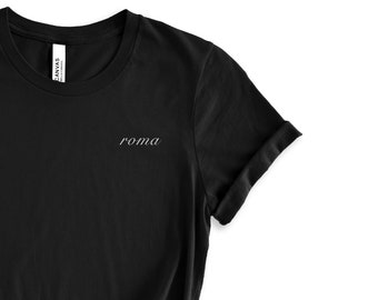 May include: Black t-shirt with a white embroidered word "roma" on the front.