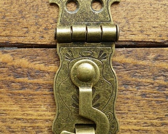 May include: Antique brass latch with a decorative design and a hook. The latch has a hinge and a small knob.