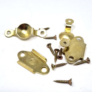 May include: A set of gold-toned metal picture frame hardware with screws. The hardware includes two corner brackets, one curved bracket, and one straight bracket.