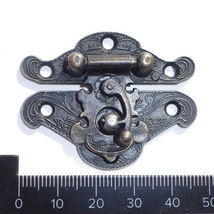 May include: Antique-style metal latch with ornate floral designs and a decorative knob. The latch is in a dark bronze finish and measures approximately 7.5 cm in length.