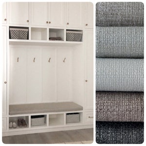 May include: White entryway bench with storage shelves and a cushioned seat. The bench is built into a white cabinet with two doors and a shelf above. The cabinet has brass knobs. Two woven baskets are on the shelf. There are three brass hooks on the wall above the bench.
