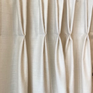 May include: White curtains with pleats hanging from a clear acrylic rod with black rings.