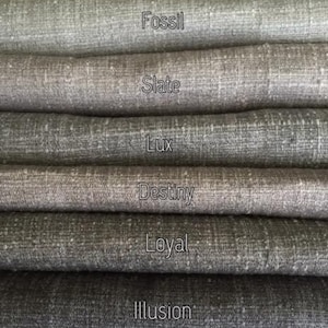May include: Close-up of eight fabric swatches in various shades of gray, from light to dark. The swatches are labeled with the names "Classic", "Fossil", "Slate", "Lux", "Destiny", "Loyal", "Illusion", and "Chiffon".