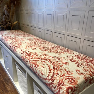 May include: White bench with storage bins and a red and cream patterned cushion.