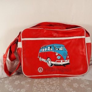 May include: Red messenger bag with white trim and a red shoulder strap. The bag features a graphic of a red and blue Volkswagen bus with the word "Volkswagen" below the graphic.