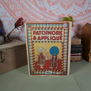 May include: A vintage book titled "Patchwork & Appliqué" with a colourful patchwork design on the cover. The cover features two children in vintage clothing holding flowers. The book is published by Golden Hands.