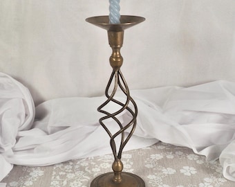 Può includere: Un portacandele vintage in ottone con un design a spirale sullo stelo. Il supporto ha una base rotonda e un piccolo piatto per contenere una candela. Una candela blu chiaro a spirale è nel supporto.