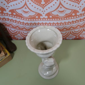 K&ouml;nnte beinhalten: Wei&szlig;e Keramikvase mit einer Skulptur einer Frau, die eine Schale h&auml;lt. Die Vase hat eine glatte, gl&auml;nzende Oberfl&auml;che.