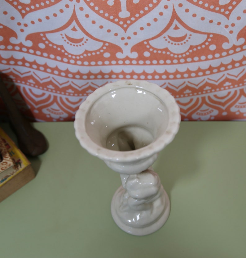 K&ouml;nnte beinhalten: Wei&szlig;e Keramikvase mit einer Skulptur einer Frau, die eine Schale h&auml;lt. Die Vase hat eine glatte, gl&auml;nzende Oberfl&auml;che.