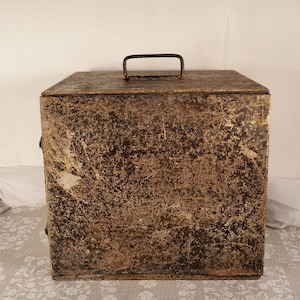 May include: A rectangular metal storage box with a hinged lid and a black handle. The box has a distressed, mottled brown and gold finish, showing signs of wear. The box is likely used for storage.