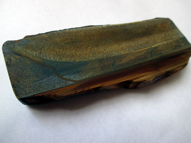 May include: A long, rectangular piece of polished stone with a blue and brown pattern. The stone has a rough, natural edge.