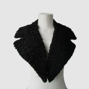 Peut inclure: Un col en fausse fourrure noire avec un revers cranté. Le col est présenté sur un mannequin blanc, mettant en valeur sa forme et sa texture. Le col est un accessoire de mode.