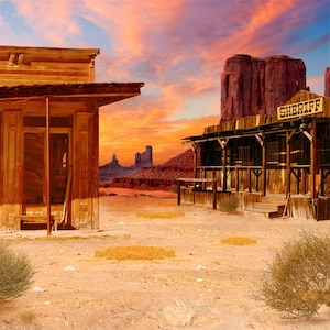 May include: A vintage Western-style town scene with two wooden buildings, one labeled "SHERIFF", set against a backdrop of red rock formations and a sunset sky.