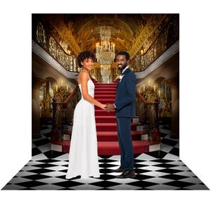 May include: A couple poses on a grand staircase with a red carpet runner. The background features a gold and white ornate design with a large chandelier.