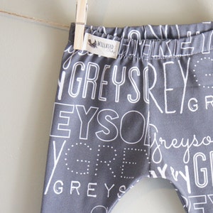 K&ouml;nnte beinhalten: Graue Baby-Leggings mit einem wei&szlig;en Druck des Wortes "grau", das in verschiedenen Schriftarten und Gr&ouml;&szlig;en wiederholt wird.