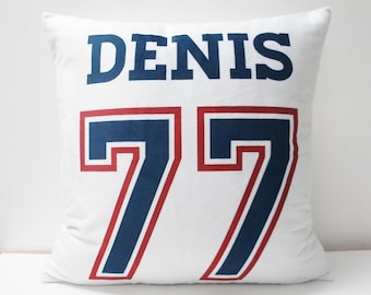 May include: White pillow with the name "DENIS" and the number "77" in blue and red lettering.
