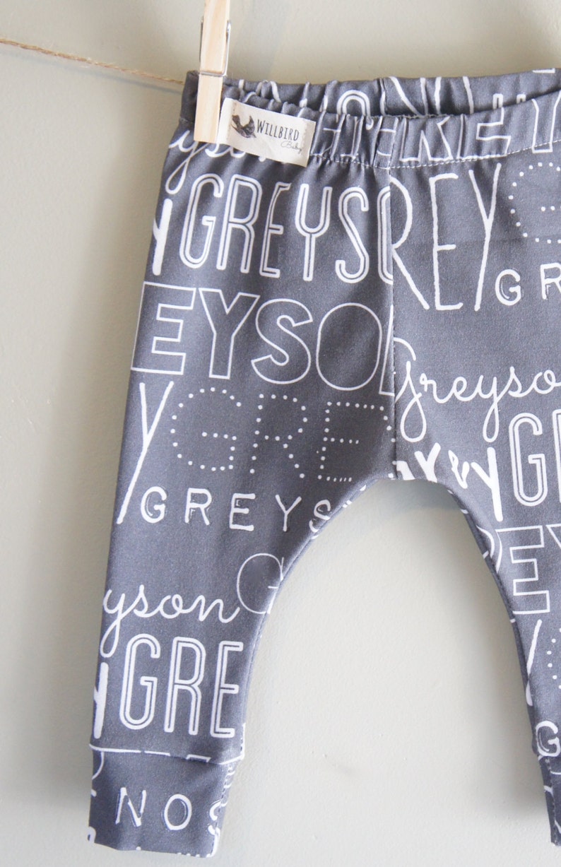 K&ouml;nnte beinhalten: Graue Baby-Leggings mit einem wei&szlig;en Druck des Wortes "grau", das in verschiedenen Schriftarten und Gr&ouml;&szlig;en wiederholt wird.