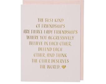 May include: A greeting card with a light pink background and a darker pink border. The text in gold reads: "THE BEST KIND OF FRIENDSHIPS ARE FIERCE LADY FRIENDSHIPS...THE OTHER DESERVES THE WORLD."