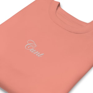 Könnte beinhalten: Ein korallenfarbener Pullover mit dem Wort "Count" in weiß auf der Vorderseite gestickt.