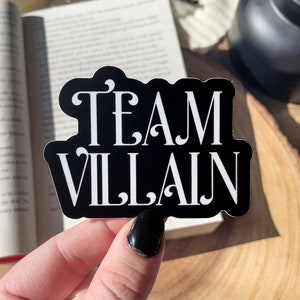 May include: Black and white sticker with the text "TEAM VILLAIN" in a decorative font.