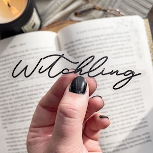 May include: A clear sticker with the word "Witchling" written in black cursive script.