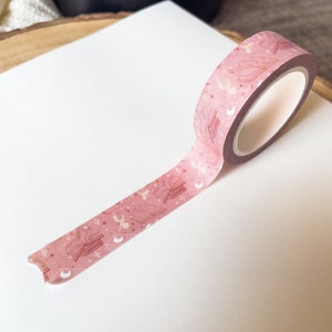May include: Pink washi tape with a pattern of open books, stars, and crescent moons.
