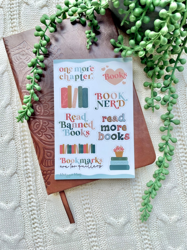 May include: A set of colorful book-themed stickers with phrases like "one more chapter", "Book Nerd", "Read Banned Books", and "Read More Books". The stickers are on a white background and feature a variety of book-related illustrations.