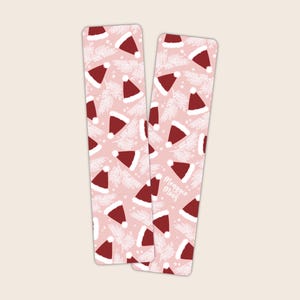 May include: Two pink bookmark with a white and red pattern of Santa hats and pine branches. The text "Maggie Moos" is on one bookmark.