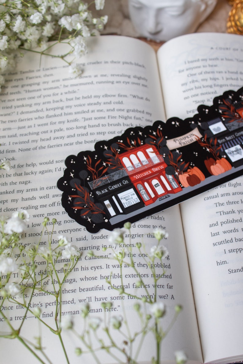 May include: Two illustrated stickers featuring a black and red storefront with the text "Black Candle Co." and "Witches Brew" on a black background with stars and leaves. The text "Pumpkin Patch" is on a banner above the storefront.