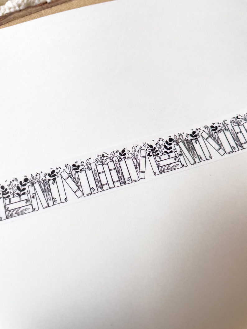 K&ouml;nnte beinhalten: Schwarz-wei&szlig;es Washi-Tape mit einem sich wiederholenden Muster aus gestapelten B&uuml;chern, aus denen Bl&auml;tter und Blumen wachsen.