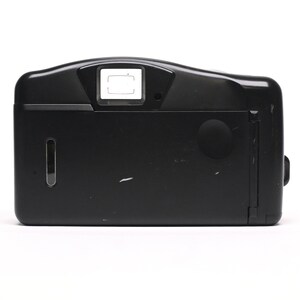 Pode incluir: C&acirc;mara de filme compacta preta com flash embutido. A c&acirc;mera tem um visor retangular e uma tampa de lente redonda.